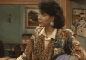 a woman in a leopard print jacket and earrings is sitting in a living room .