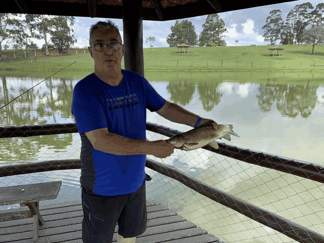 a man in a blue shirt holding a fish in his hands