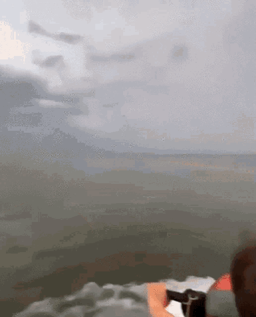 a person in a boat is taking a picture of a storm in the ocean .