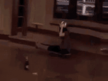 a man is dancing in a living room with a couch and a mirror in the background .