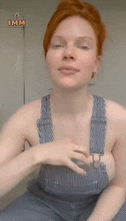 a woman with red hair is wearing overalls and a sticker that says imm
