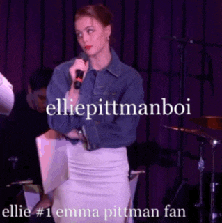 a woman holding a microphone with the words ellie pittmanboi written above her