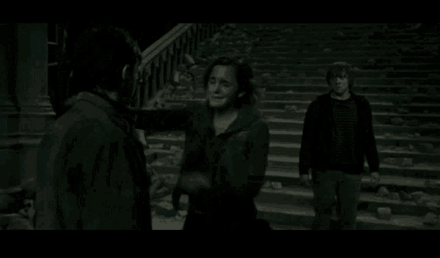 a woman is hugging a man while a man stands behind her
