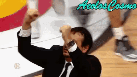 a man in a suit and tie holds his fist up in the air with the words aeolos cosmo written in the background