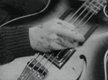 a black and white photo of a man playing a guitar
