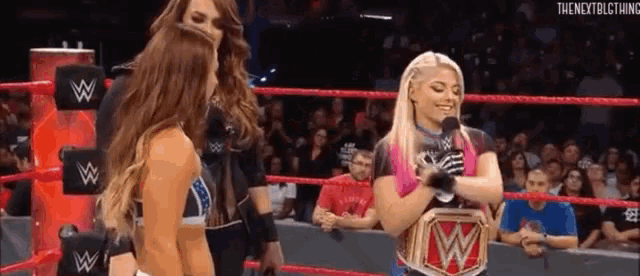 a female wrestler is talking into a microphone in a wrestling ring .