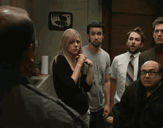a group of people standing in a kitchen with a bird on the wall behind them