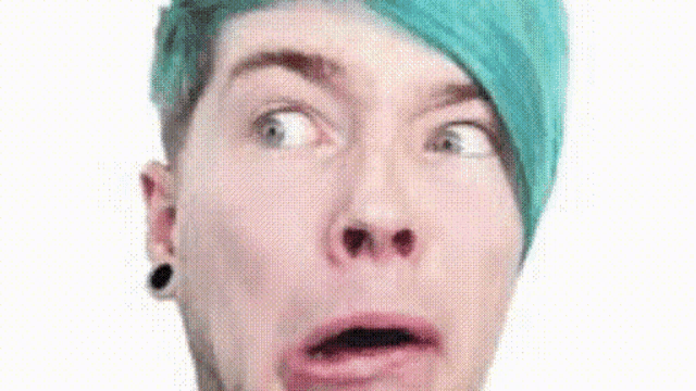 a close up of a man with blue hair making a funny face .