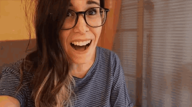 a woman wearing glasses and a blue striped shirt is smiling