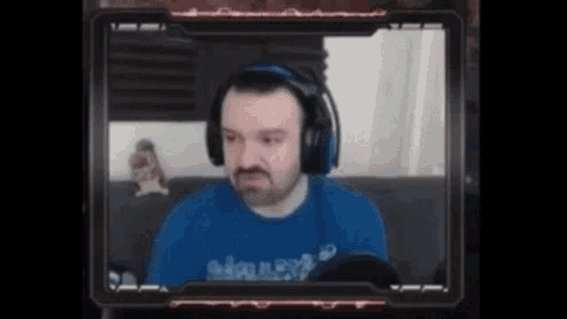 a man wearing headphones and a blue shirt is looking at the camera .