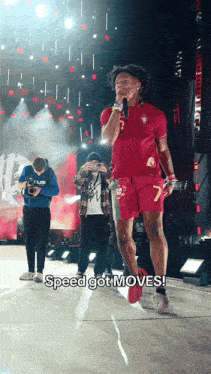 a man in a red shirt with the number 7 on it stands on a stage