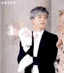 a man in a tuxedo and bow tie is holding a cat paw glove .