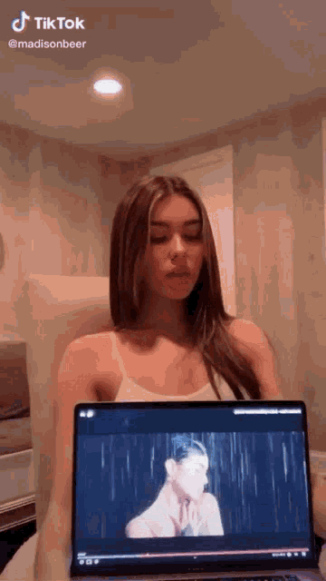 a woman is sitting in a chair watching a video on a laptop computer .