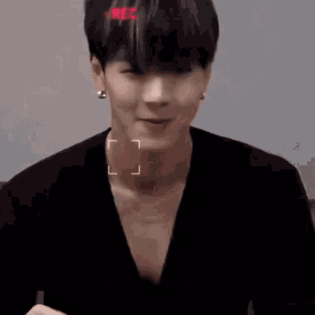 a young man is eating a piece of meat with a camera recording him .