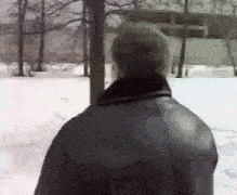 a man in a black leather jacket is standing in the snow