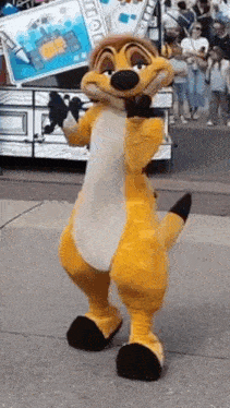 a meerkat mascot from the lion king is dancing on the sidewalk .