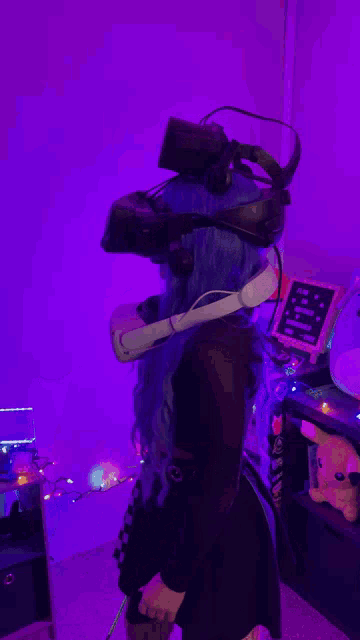 a girl with blue hair is wearing a stack of virtual reality goggles