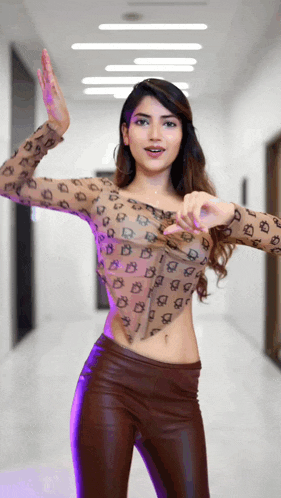 a woman wearing a leopard print top and brown pants is dancing in a hallway