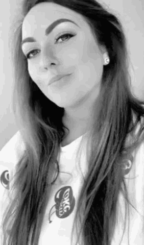 a black and white photo of a woman wearing a white t-shirt and earrings .