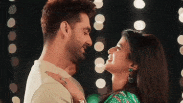 a man and a woman are looking into each other 's eyes and smiling .