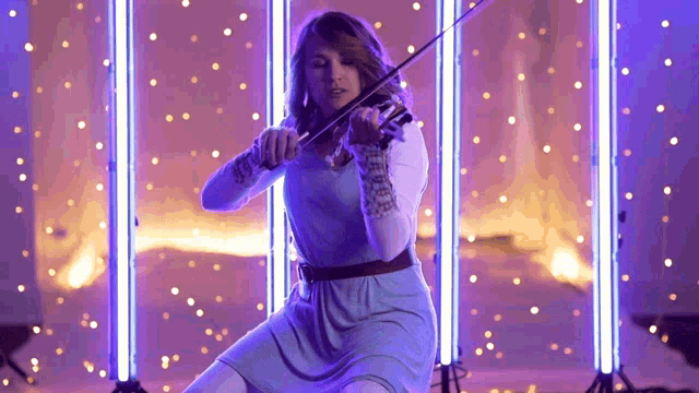 a woman in a blue dress playing a violin in front of purple lights