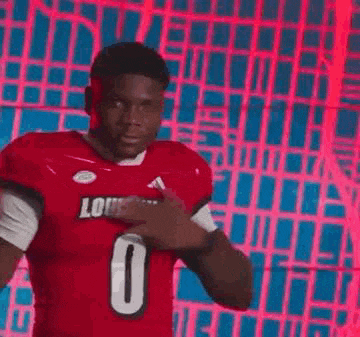 a football player in a red jersey is pointing at his chest .