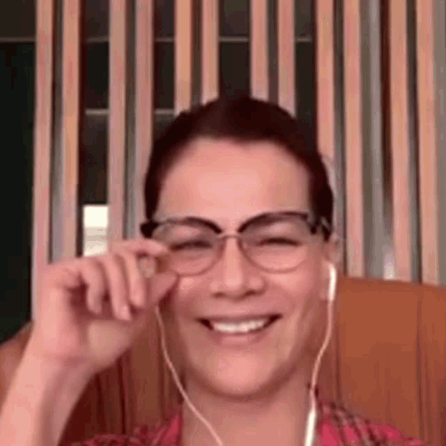 a woman wearing glasses and headphones is smiling while sitting on a chair .