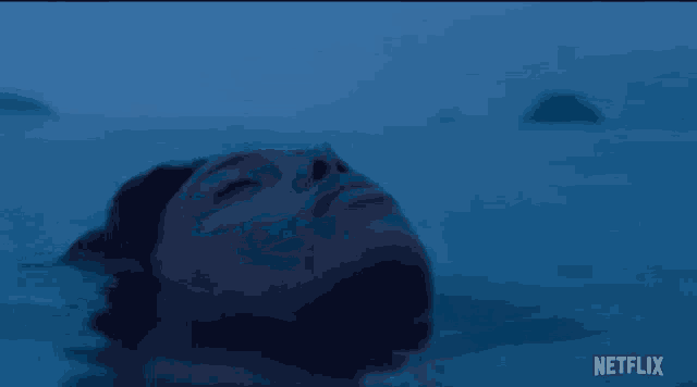 a woman is floating in the ocean with her eyes closed and her head is visible .