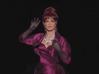 the woman is wearing a purple dress and black gloves .