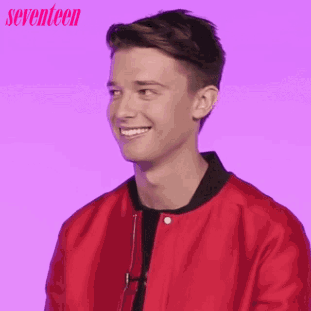 a young man is wearing a red jacket and smiling