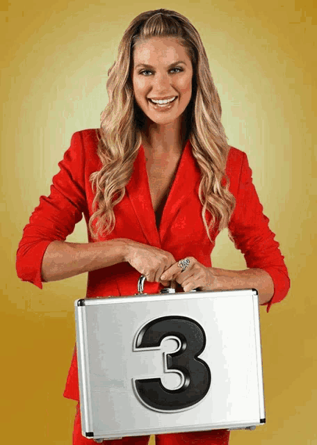 a woman in a red suit holds a silver briefcase with the number 3 on it