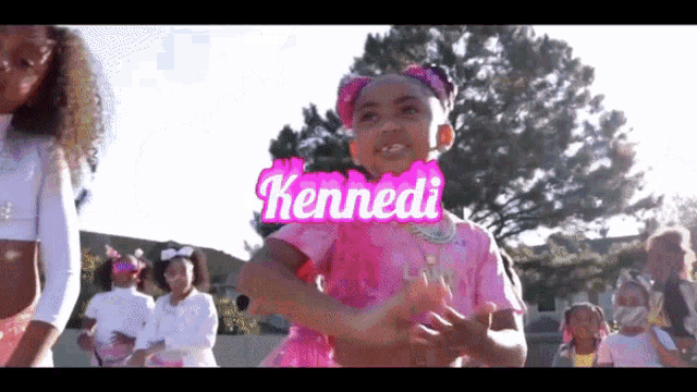 a little girl in a pink dress with the name kennedi written on it
