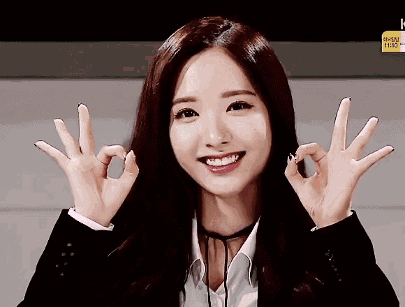 a woman making an ok sign with her hands while smiling