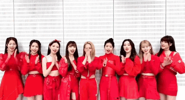 a group of girls in red dresses are standing next to each other in front of a wall .