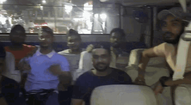 a group of men are sitting in a car and one of them is wearing a baseball cap