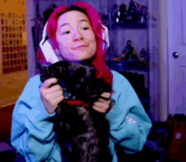 a girl with pink hair is holding a black dog