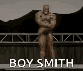 a statue of a muscular man is standing on a stage with the words `` boy smith '' written on the bottom .