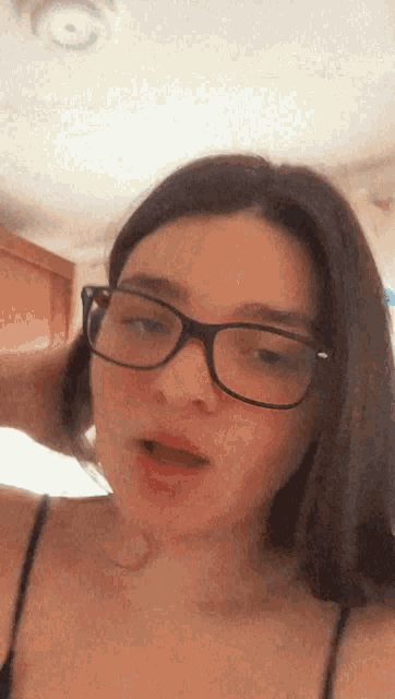a woman wearing glasses looks at the camera with her mouth open