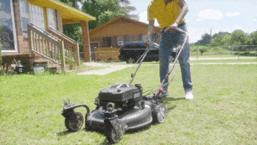 a man in a yellow shirt is mowing his lawn with a black lawn mower