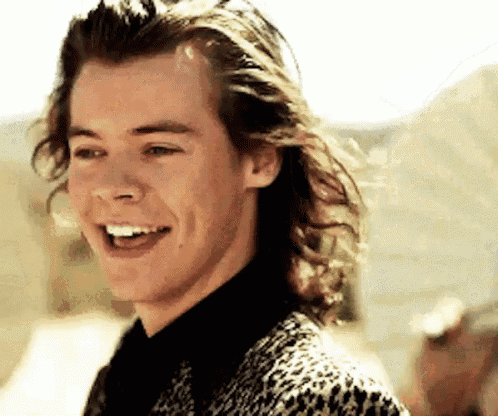 a man with long hair is smiling and wearing a leopard print jacket .