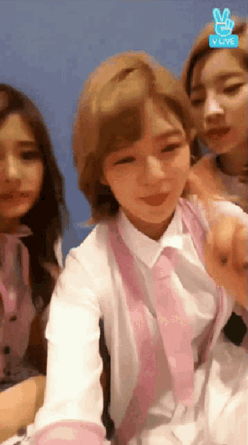 a group of girls are sitting in front of a blue wall and a sign that says v live on it