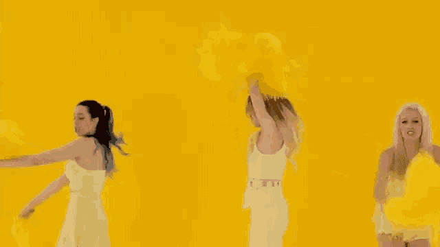 three women are dancing together in front of a yellow background .