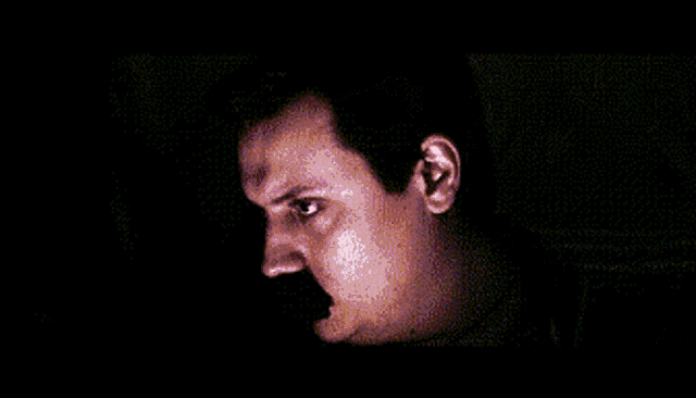 a close up of a man 's face with a mustache in the dark