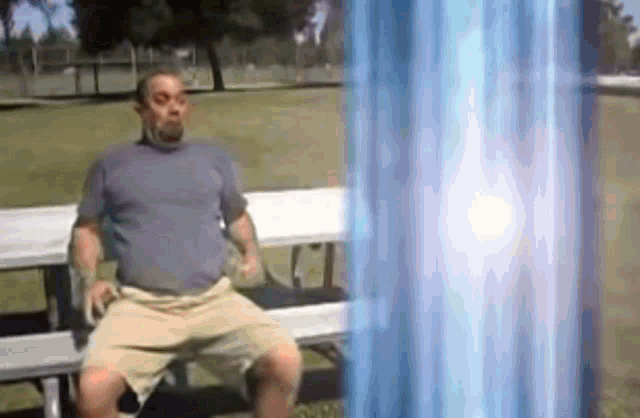 a man is sitting on a bench with a blue light coming from behind him