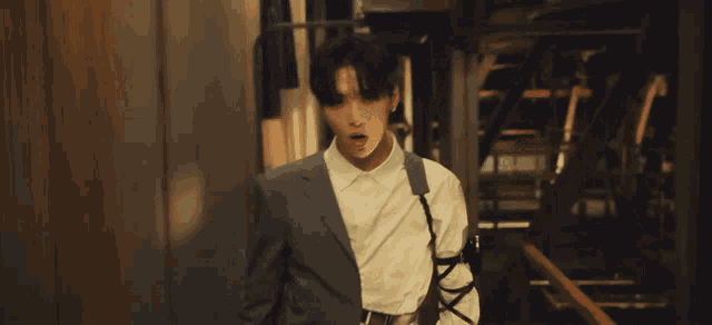 a man in a suit and white shirt is standing in a dark room looking at the camera .