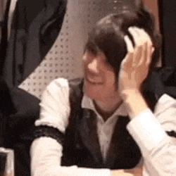 a woman wearing headphones is sitting at a table with her hand on her head .