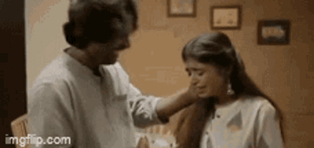 a man is touching a woman 's face in a room .