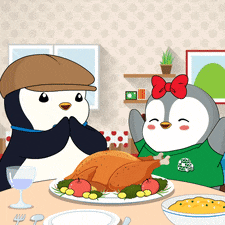 a couple of penguins sitting at a table with a turkey on it