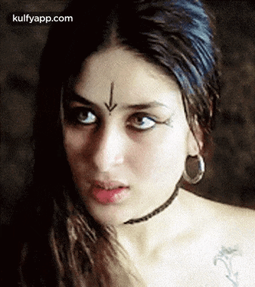 a close up of a woman 's face with a tattoo on her forehead and earrings .