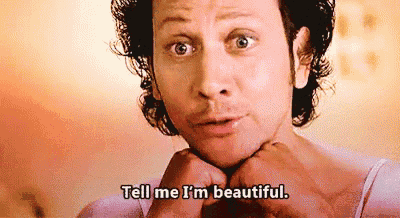 a man with curly hair is making a face and says `` tell me i 'm beautiful '' .